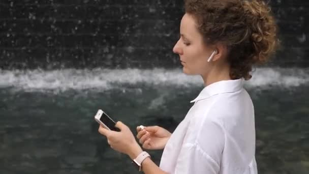 Frau verbindet drahtlose Kopfhörer mit Smartphone und Smartwatch — Stockvideo