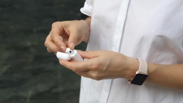 Női kéz üzembe Airpods Vezeték nélküli fülhallgató töltési esetben — Stock videók