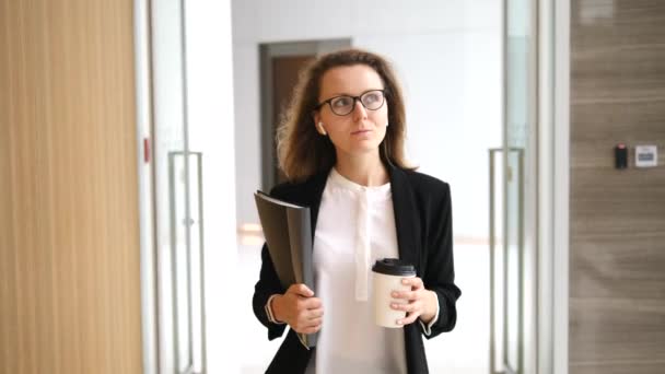 Уверенная деловая женщина в беспроводных наушниках собирается работать с кофе — стоковое видео