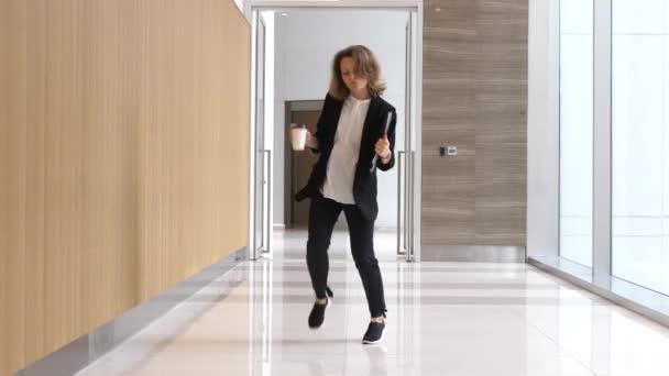 Empresária engraçada dançando em fones de ouvido sem fio com copo de café — Vídeo de Stock