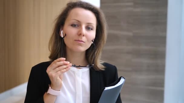 Портрет красивой деловой женщины с беспроводными наушниками в офисном зале — стоковое видео
