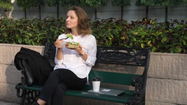 Feliz joven mujer de negocios comiendo una ensalada saludable en el almuerzo — Vídeo de stock