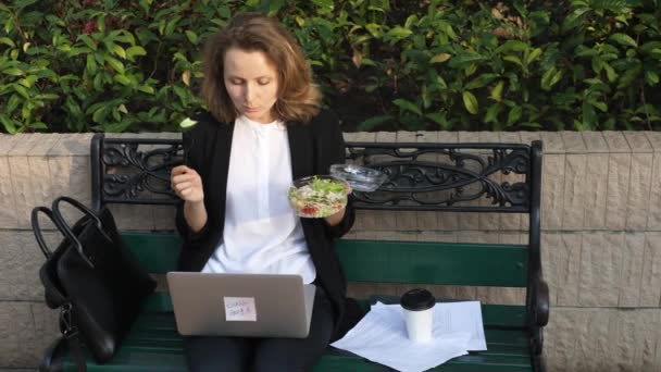 Üzleti nő eszik saláta ebédszünetben a City Parkban Élő egészséges életmód — Stock videók