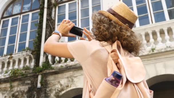 Mujer joven tomando fotos con Smartphone mientras visita la ciudad — Vídeo de stock
