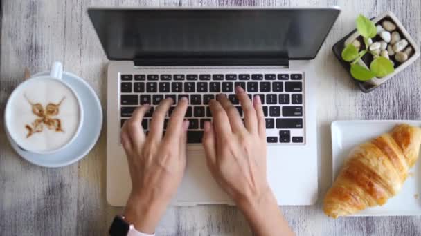 Vista superior de las manos femeninas escribiendo en el teclado del ordenador portátil en Coffee Break — Vídeo de stock