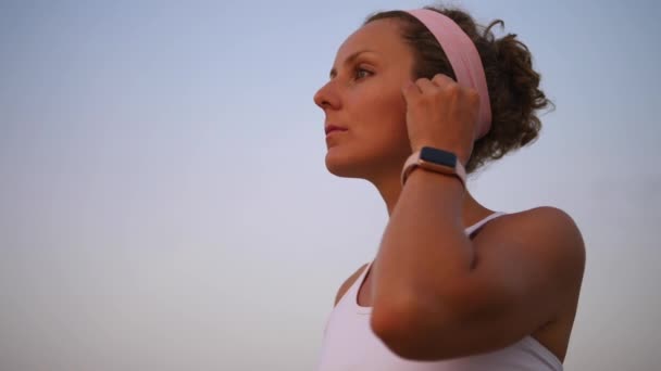 Άσκηση γυναίκα φορώντας SmartWatch και ακούγοντας μουσική σε ασύρματα ακουστικά Εξωτερικές πόρτες — Αρχείο Βίντεο