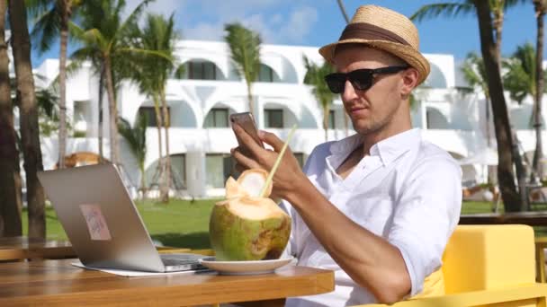 Succesvolle man met behulp van smartphone Werken met laptop op het strand in Villa — Stockvideo