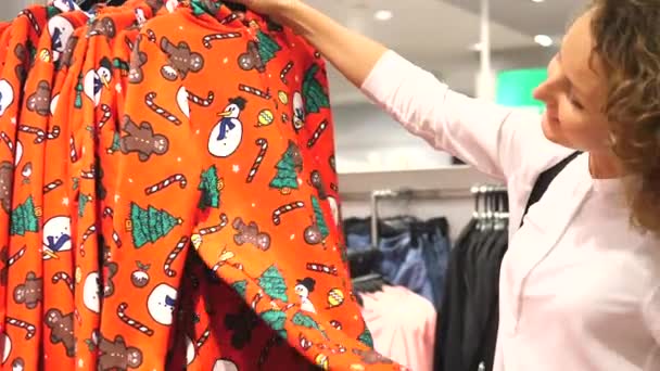 Julshopping. Glad flicka väljer röd Xmas tröja. — Stockvideo