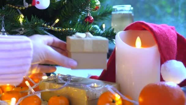 Женская рука кладет подарки под елку — стоковое видео