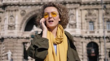 Şehirdeki sokakta yürüyen cep telefonundan arayan genç bir kadın.