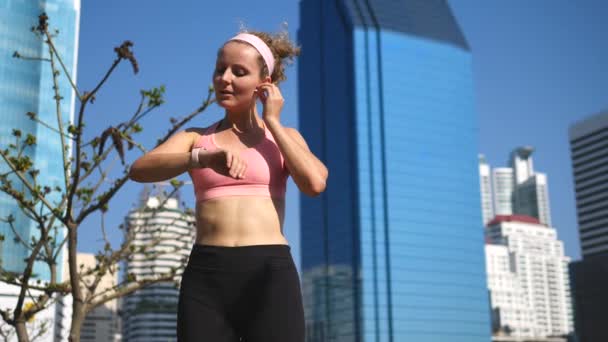 Sport Woman Korzystanie Smartwatch i bezprzewodowe słuchawki ćwiczenia w City Park — Wideo stockowe