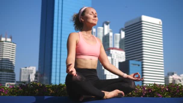 Junge Fitness-Frau meditiert und übt Yoga im Stadtpark — Stockvideo