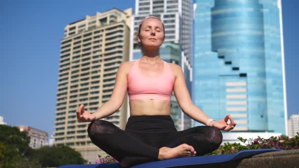 Mujer joven y saludable meditando y haciendo yoga en la ciudad al aire libre — Vídeo de stock