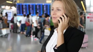 Havaalanında cep telefonuyla konuşan genç bir iş kadını.