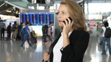 İş gezisindeki genç iş kadını havaalanında akıllı telefondan konuşuyor.