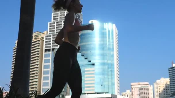 Femme sportive courant en plein air contre fond de ville moderne — Video