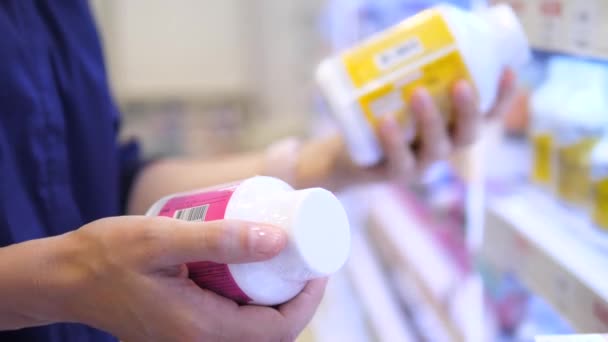 Primer plano de las manos del cliente femenino que elige la medicación en la farmacia — Vídeos de Stock