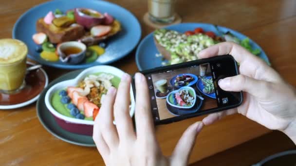 Tendências do pequeno-almoço. Blogueiro feminino tirando fotos de alimentos com celular no café — Vídeo de Stock