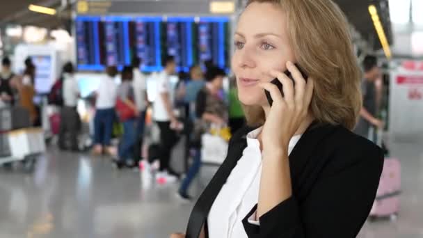 Молодая деловая женщина разговаривает по мобильному телефону в аэропорту — стоковое видео