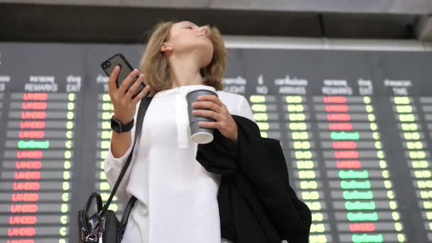 Jonge zakenvrouw met behulp van Smartphone bij vertrek Dienstregeling weergeven op de luchthaven — Stockvideo