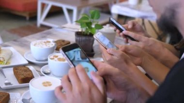 Kafede birlikte kahve içerken akıllı telefonları kullanan arkadaşlar.