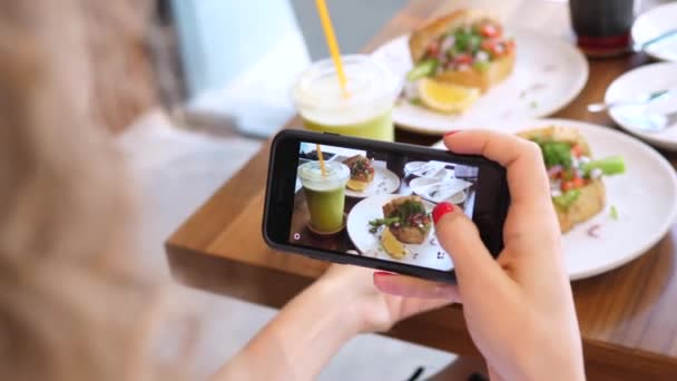 Žena Food Blogger Fotografování Vegan zdravé potraviny mobilním telefonem v kavárně — Stock video