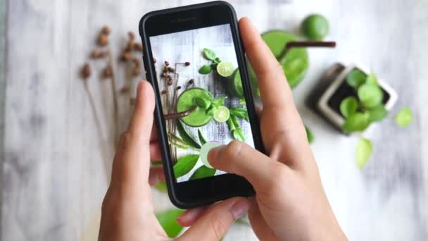 Manos tomando foto de batido verde con teléfono inteligente — Vídeos de Stock