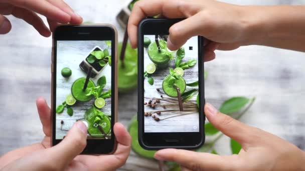 Manos de amigos tomando foto de comida de batido verde con teléfono inteligente en el café — Vídeo de stock