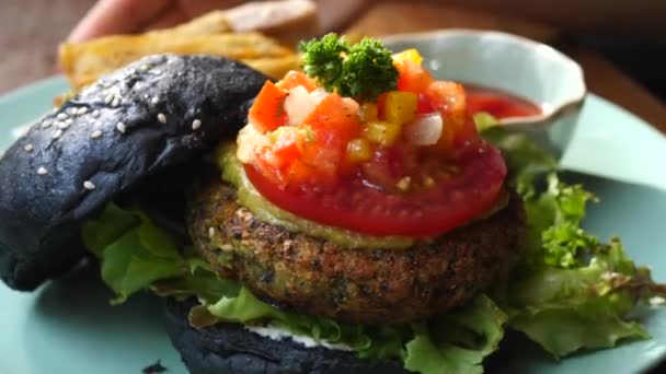 Primer plano de hamburguesa vegetariana con pan negro en restaurante vegano . — Vídeo de stock