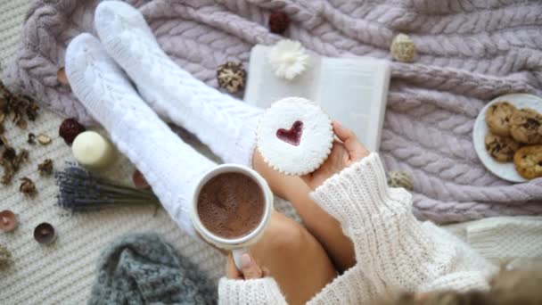 Mujer en calcetines de punto bebiendo chocolate caliente con galletas en casa — Vídeos de Stock