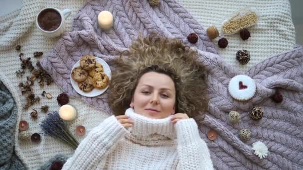 Веселая молодая женщина в трикотажном свитере лежит на кровати — стоковое видео