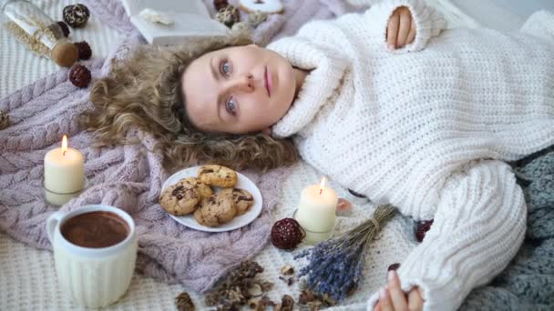 Молодая женщина лежит на кровати в вязаном свитере . — стоковое видео