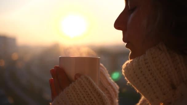 Kvinna som håller varm kopp te eller kaffe utomhus vid solnedgången. Mysigt vinterkoncept. — Stockvideo