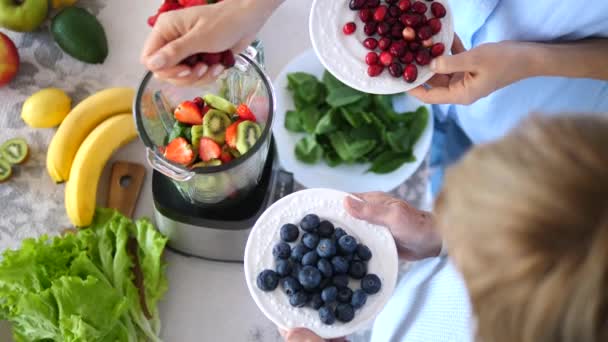 Женщины готовят здоровый зеленый смузи с ягодами — стоковое видео