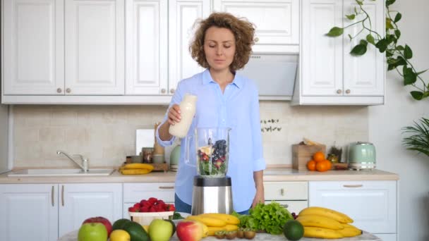 Sorrindo menina fazendo Smoothie saudável na cozinha despejando leite vegetal — Vídeo de Stock