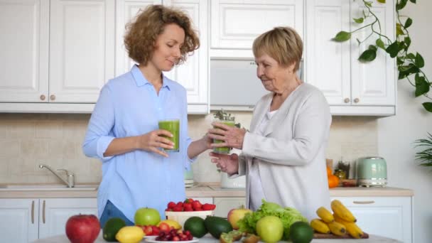 Внучка и бабушка пьют здоровый зеленый смузи на кухне — стоковое видео