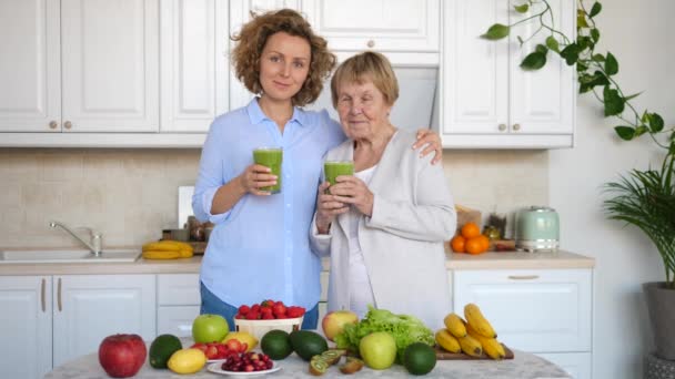 Porträt von Enkelin und Großmutter mit gesundem grünen Smoothie zu Hause — Stockvideo