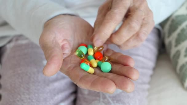 Vieja mano de la abuela sosteniendo coloridas píldoras — Vídeo de stock