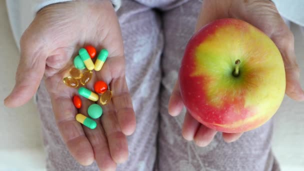 Szoros időskori női kéz tartó alma és tabletták. — Stock videók