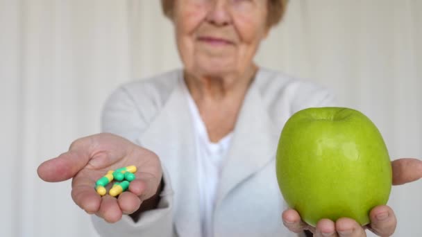 Пожилая женщина держит яблоко и таблетки в руках. Крупный план . — стоковое видео
