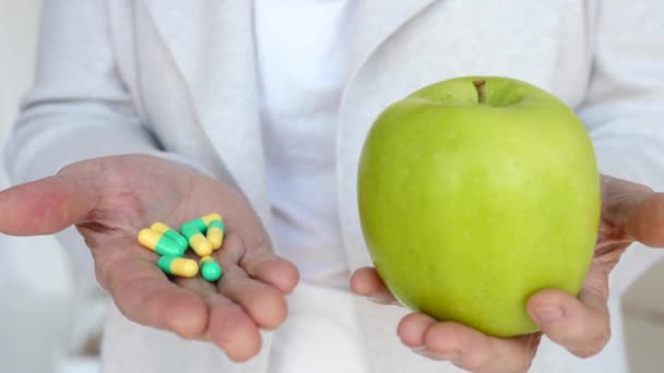 Detailní záběr na starší ženy ruce drží zelené jablko a pilulky. — Stock video