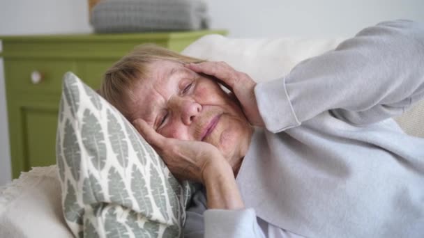 Retrato de una anciana sosteniendo la cabeza con las manos sintiendo dolor de cabeza — Vídeos de Stock