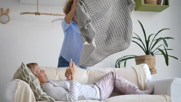 Petite-fille prenant soin de grand-mère se détendre sur le canapé avec téléphone portable — Video