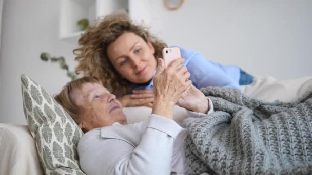 Barnbarn och mormor använder mobiltelefon tillsammans hemma — Stockvideo