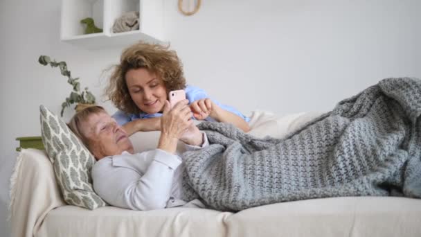 Senioren und Technologie. Enkelin und Großmutter nutzen Smartphone. — Stockvideo