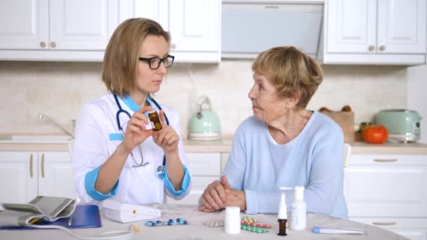 Médico mujer prescribe droga a anciano paciente mujer informa sobre las precauciones . — Vídeo de stock