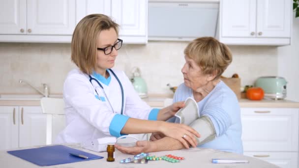 Az orvos méri az idős beteg vérnyomását. Házhoz hívás. — Stock videók