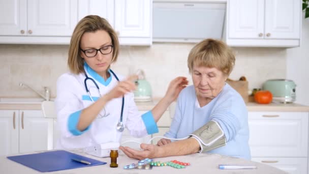 Visita al médico en casa. Cuidador Medición de la presión arterial del paciente mayor . — Vídeos de Stock