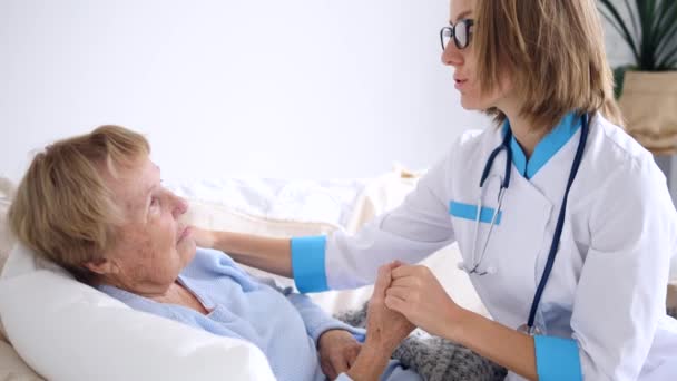 年轻医生安慰家中的老年女性病人 — 图库视频影像