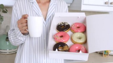 Kadın eli çörekleri tutuyor ve kahvaltıda bir fincan kahve.